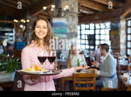 Gerne schöne Kellnerin Clients in einem eleganten Restaurant. Stockfoto