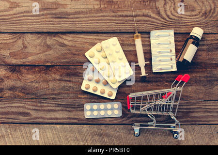 Warenkorb mit Pillen, die Spritze auf dem alten Holz Hintergrund. Getönten Bild. Stockfoto