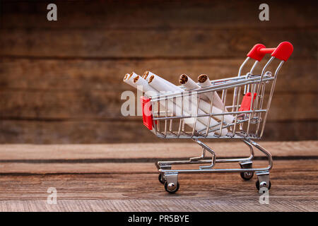 Shopping Cart mit Zigarette auf dem alten Holz Hintergrund. Getönten Bild. Stockfoto