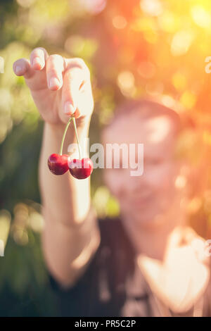 Zwei Beeren von reifen Kirschen in den Händen eines Mädchens Stockfoto