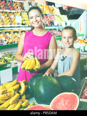 Lächelnde Frau mit Tochter kaufen Bananen Obst im Supermarkt Stockfoto