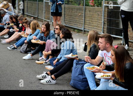 London, Großbritannien - 27 August 2018: Notting Hill Carnival Gruppe Teens und köstliches Essen auf der Straße sitzen Stockfoto