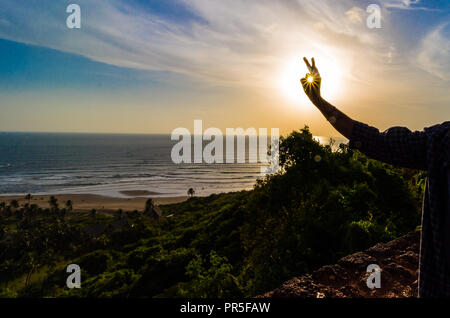 Vagator Beach - Sonnenuntergang Strahlen in den Rahmen um die Grüne natürliche Schönheit von Goa, Indien erfasst. Stockfoto