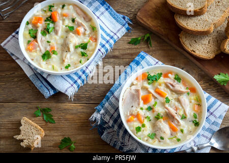 Huhn und wilder Reis Suppe. Hausgemachte frische cremige Suppe mit Hähnchen, Gemüse und Wildreis in weiße Schüssel, Ansicht von oben. Stockfoto