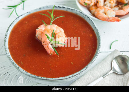 Pflanzliche Tomatensuppe Gazpacho mit Garnelen (Garnelen) und Rosmarin in der Schüssel auf weißem Holz- Hintergrund, Ansicht von oben, kopieren. Stockfoto