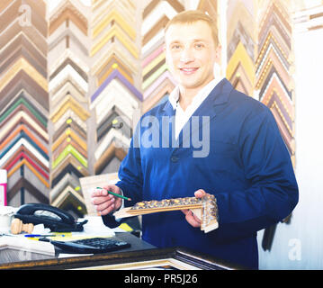 Portrait von froh europäischen Mann Verkäufer arbeiten mit Bilderrahmen im Atelier Stockfoto
