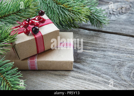 Weihnachten Rahmen aus grünen Zweigen der Fichte, Tannenzapfen, Geschenkboxen mit Stechpalme Beeren auf dem Hintergrund der Holzbretter, mit copy-Platz. Stockfoto