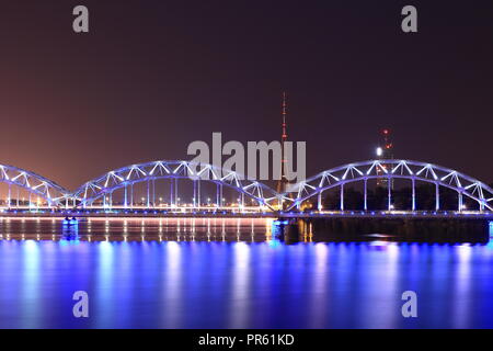 Riga, Lettland - 20.September 2018: ein Wahrzeichen für die Eisenbahnbrücke und dem Rigaer Radio-TV Tower, dem höchsten Punkt erreicht 368 Meter, in der Nacht. Stockfoto