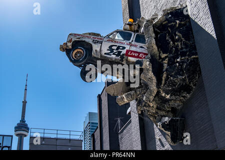 Ein Stück der Street Art der Darstellung einen Nachrichten Fahrzeug platzen aus der Wand der Glocke Medien HQ in der Innenstadt von Toronto Stockfoto