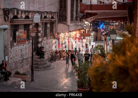 Damaskus/Syrien: Nacht Foto einer schmalen Gasse in der Altstadt in der Nähe der Omaijadenmoschee in Bab Touma mit Menschen gehen unter den Straßenlaternen. Stockfoto