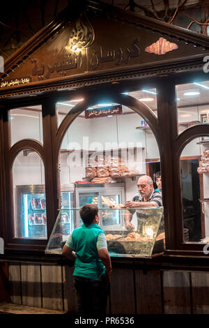 Damaskus/Syrien - 25/07/2018: Nacht Foto eines Kindes kauf Croissant aus einem Croissant Shop in einer schmalen Gasse in der Altstadt in der Nähe der Omayyaden-moschee. Stockfoto