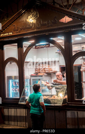 Damaskus/Syrien - 25/07/2018: Nacht Foto eines Kindes kauf Croissant aus einem Croissant Shop in einer schmalen Gasse in der Altstadt in der Nähe der Omayyaden-moschee. Stockfoto