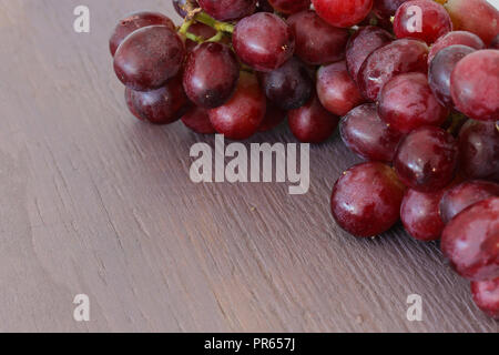 Ein Strauß roter kernlose Trauben auf einem violetten Holz Hintergrund Stockfoto