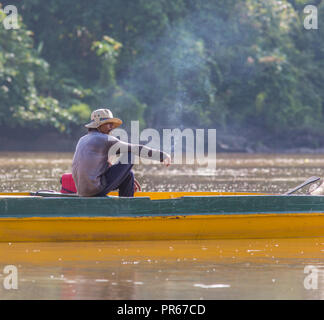 Ein Fischer in ruhiger Rauch auf dem friedlichen Fluss Kinabatangan in Sabah Borneo Stockfoto