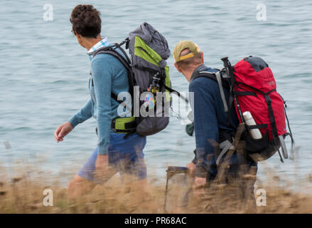 Ein paar oder Mann und Frau zwei Rucksacktouristen zu Fuß entlang der Klippe auf der Insel Wight coastal path. Stockfoto