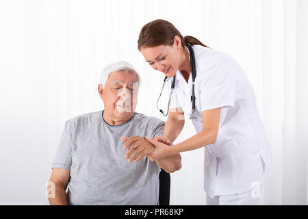 Junge Ärztin Prüfung von männlicher Patient Puls in der Klinik Stockfoto