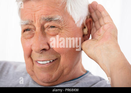 Portrait eines älteren Mannes Hand versucht nach dem Einlegen Hörgerät zu hören Stockfoto