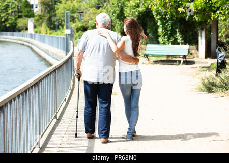 Nahaufnahme einer Frau Unterstützung ihr Vater beim Gehen mit Stock Stockfoto