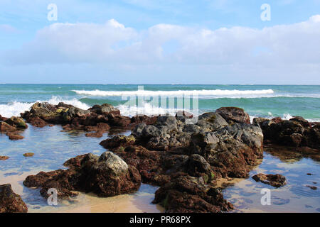 Kleine Wellen auf einem vulkanischen Felsen in Paia Bay, Maui, am Anfang der Straße nach Hana Stockfoto