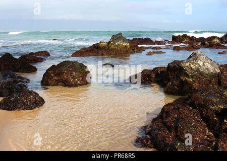 Kleine Wellen auf einem vulkanischen Felsen in Paia Bay, Maui, am Anfang der Straße nach Hana Stockfoto