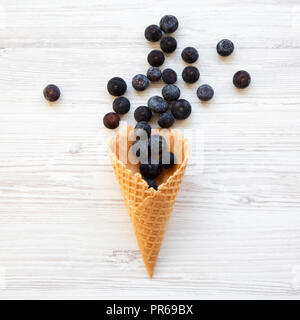 Süße Waffel Eiswaffel mit Blaubeeren auf weißem Holz- Tabelle, Ansicht von oben. Von oben, Overhead, flach. Stockfoto