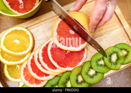 Hände Hausfrauen Frauen mit einem Messer frische Grapefruit auf dem Schneidebrett der Küchentisch Schnitt Stockfoto