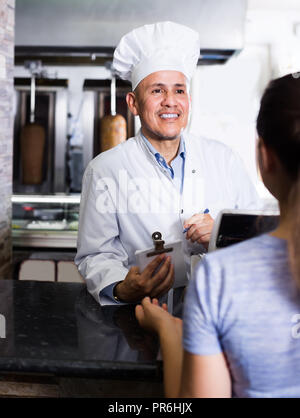 Reife Männer kochen in der Nähe der Kasse, Auftrag vom Kunden im Cafe Zähler Stockfoto