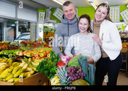 Freundliche Familie mit jugendlichen Tochter stehen mit voller Lebensmittelgeschäftkarre nach dem Einkaufen in Obst speichern Stockfoto