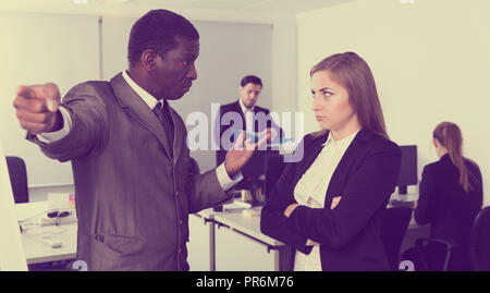 Unglückliche Frau Manager hören wütenden Mann Chef pointinting zu vermisst in Arbeit Stockfoto