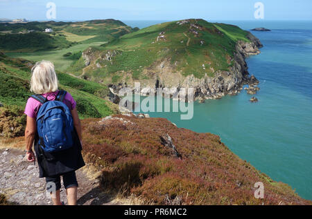 Frau Wanderer nach Westen entlang der Küste über Porth Llanlleiana Bay auf der Isle of Anglesey Coastal Path in Wales, Großbritannien. Stockfoto