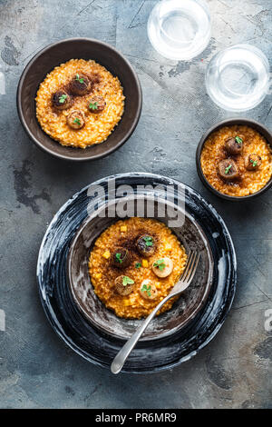 Risotto mit Kürbis und Jakobsmuscheln in einer Schüssel auf dem Tisch. horizontale Ansicht von oben Stockfoto