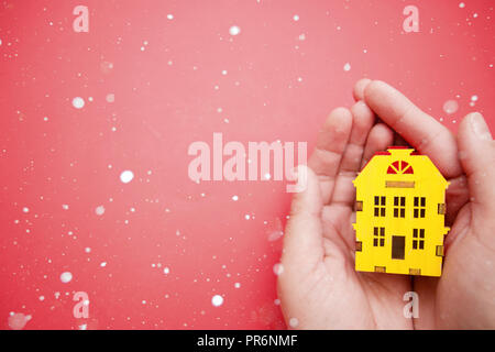 Gelbes Haus Modell in weibliche Hände auf rotem Hintergrund. Stockfoto