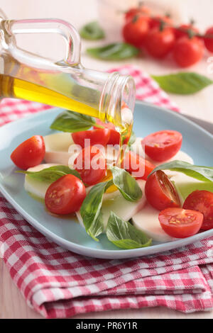 Caprese Salat mit Mozzarella, Cherry Tomaten und Basilikum auf blauen Platte Stockfoto