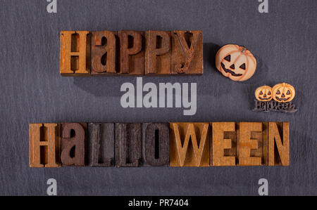 Happy Halloween Text in Holzblock Briefe mit Kürbis Symbole auf schwarzem Hintergrund Stockfoto