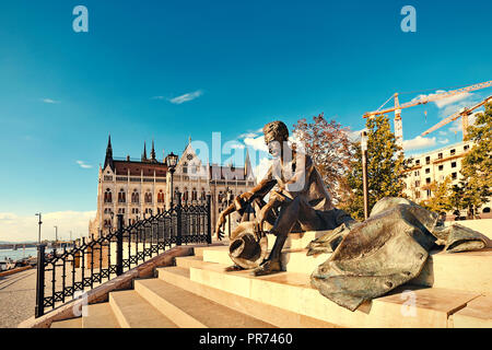 Statue des berühmten ungarischen Dichters Attila József in Budapest mit dem Haus des Parlaments im Hintergrund. Stockfoto