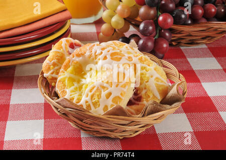 Ein Korb mit kleinen dänischen Gebäck auf einem Tisch mit Platten Stockfoto