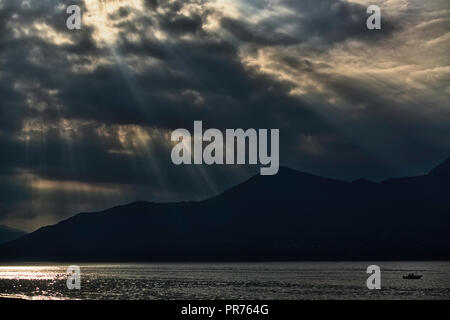 Hintergrundbeleuchtung Panorama mit Sonnenstrahlen bei Sonnenuntergang über die Berge und den Lago Maggiore Stockfoto