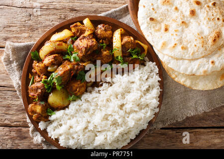 Traditionelles Rezept für Indische chicken do pyaza (dopiaza) mit Zwiebeln und Gewürzen und Garnieren von Reis close-up auf einem Teller mit Fladenbrot auf einen Tisch. Horiz. Stockfoto