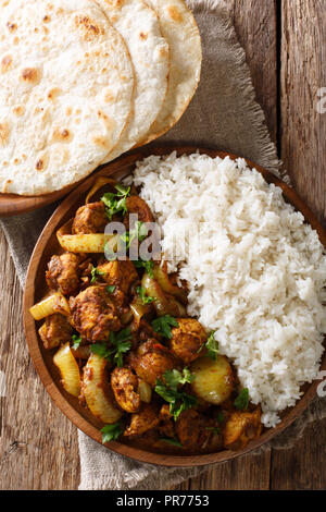 Traditionelles Rezept für Indische chicken do pyaza (dopiaza) mit Zwiebeln und Gewürzen und Garnieren von Reis close-up auf einem Teller mit Fladenbrot auf einen Tisch. Verti Stockfoto