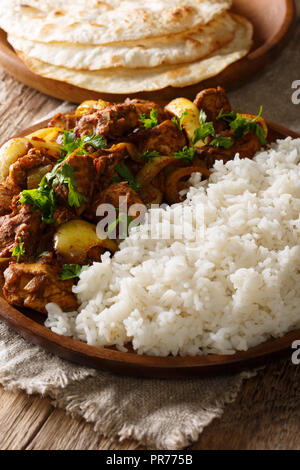 Chicken do pyaza (dopiaza) Zwiebel und Tomate Soße zusammen mit Gewürzen mit Reis und Fladenbrot auf einem Tisch serviert, gekocht wird. Vertikale Stockfoto