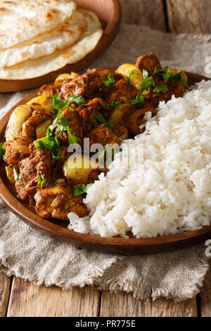 Traditionelles Rezept für Indische chicken do pyaza (dopiaza) mit Zwiebeln und Gewürzen und Garnieren von Reis close-up auf einem Teller mit Fladenbrot auf einem Tisch. Verti Stockfoto