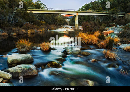 Fließend kaltes Wasser auf Verschneiten Flüsse während der eisige Winter Saison unter Gathega Damm in SNowy Mountains in Australien zwischen Felsbrocken fließt. Stockfoto