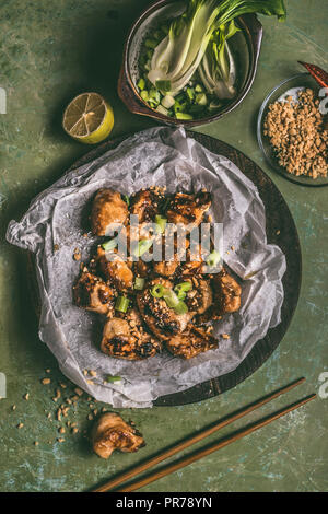 Nahaufnahme der Fried Chicken Teriyaki Stücke mit Erdnussbutter und Frühlingszwiebeln auf Tisch Hintergrund mit Stäbchen und Zutaten. Asiatische Lebensmittel Konzept Stockfoto