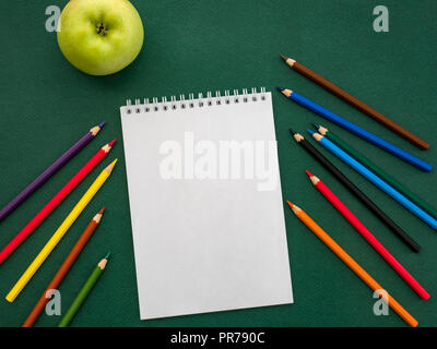 Blick von oben auf die leere Notebook, Buntstifte und grüner Apfel. Zurück zum Konzept der Schule Stockfoto