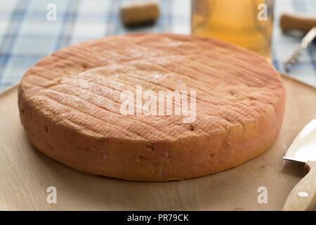 Ganze traditioneller französischer Münsterkäse auf einem Schneidebrett Stockfoto