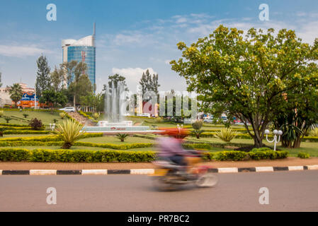 Kigali, Ruanda - September 20, 2018: Ein oto' (Motorrad) an einem Kreisverkehr in der Nähe zum Stadtzentrum, mit Kigali City Tower im Hintergrund Stockfoto