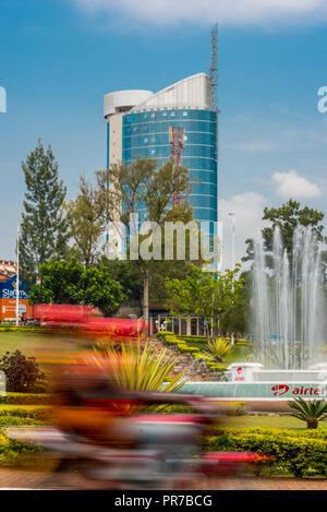 Kigali, Ruanda - September 20, 2018: Ein oto' (Motorrad) an einem Kreisverkehr in der Nähe zum Stadtzentrum, mit Kigali City Tower im Hintergrund Stockfoto