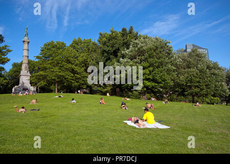 Menschen, die auf dem Gras in Boston Common Park (auf der linken Seite Soldaten und Matrosen Denkmal), Boston, Suffolk County, Massachusetts, USA Stockfoto