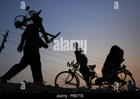 Dhaka, Bangladesch. 30 Sep, 2018. Ein Messer Kreditgeber und rikscha Abzieher Silhouette gegen die Sonne, wenn sie von der Arbeit nach Hause gehen, in der die Ausgestoßenen der Gabtoli, einer Nachbarschaft von Dhaka. Credit: MD Mehedi Hasan/ZUMA Draht/Alamy leben Nachrichten Stockfoto