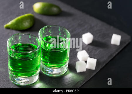 Gläser Absinth mit Limettensaft und Zucker auf schwarzem Hintergrund Stockfoto